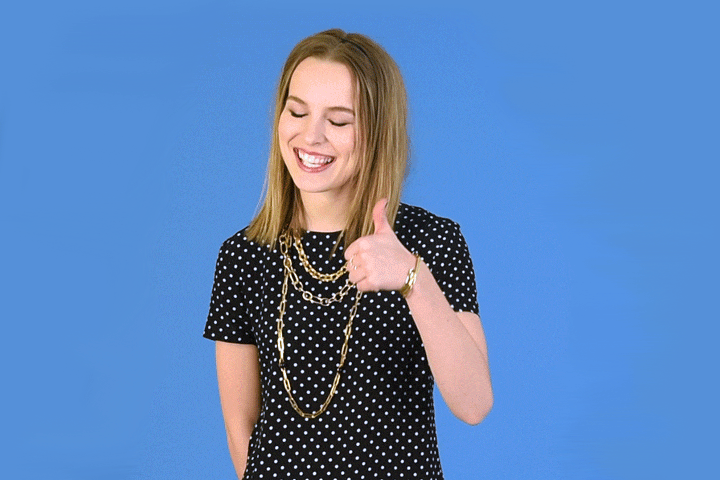 egy hölgy mosolyogva „number one” jelet mutat a hüvelykujjával